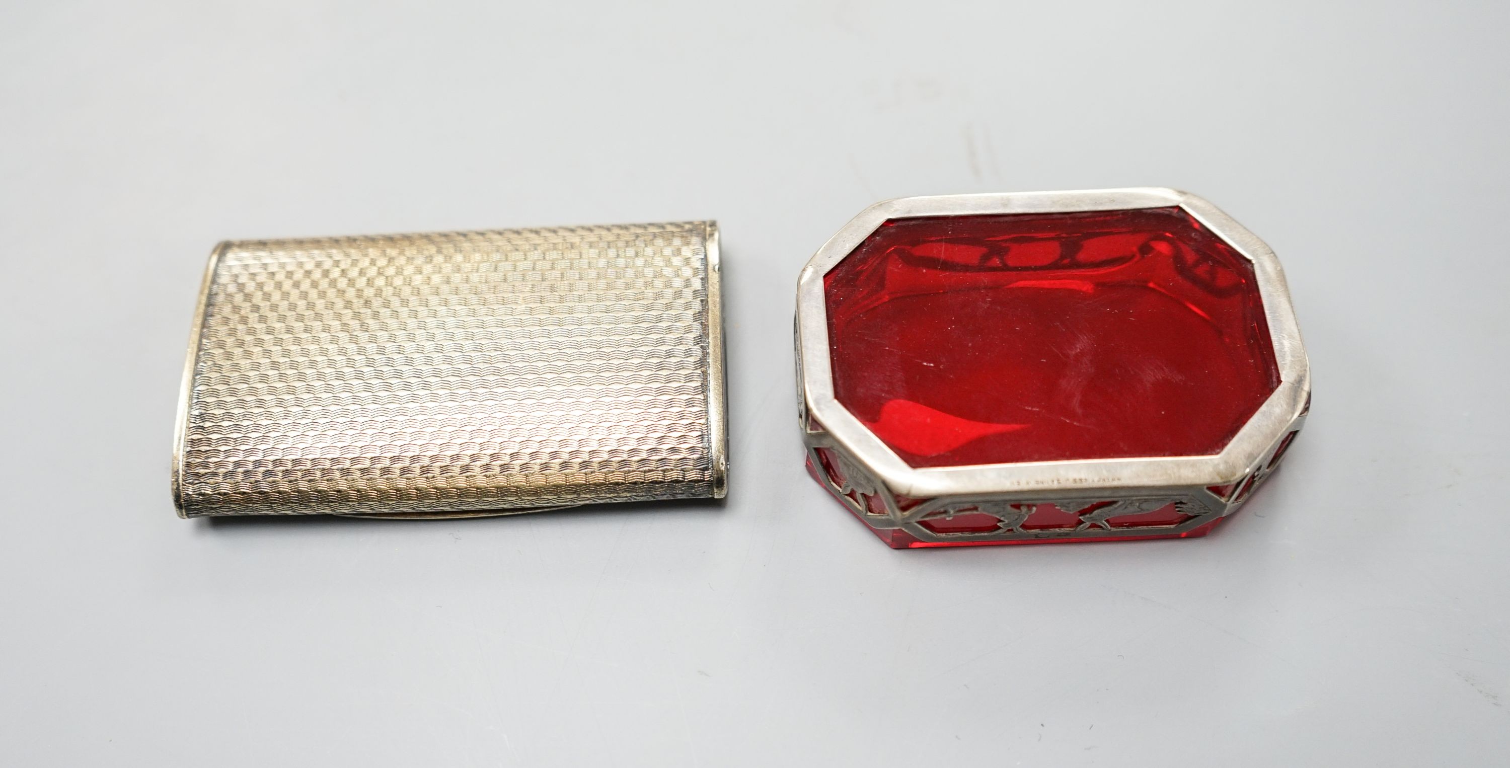 An early 20th century Austro Hungarian gilt white metal snuff box, 82mm and a similar later mounted ruby glass dish, 72mm.